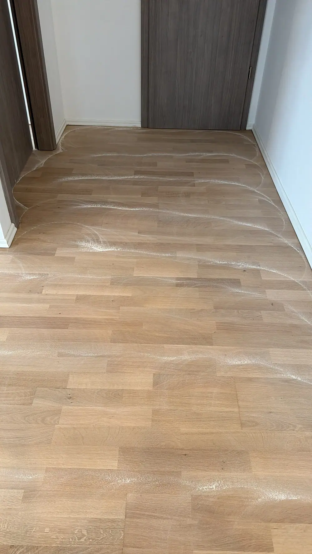 Eiche-Parkett im Flur mit sichtbaren Schleifspuren vor einer Tür.