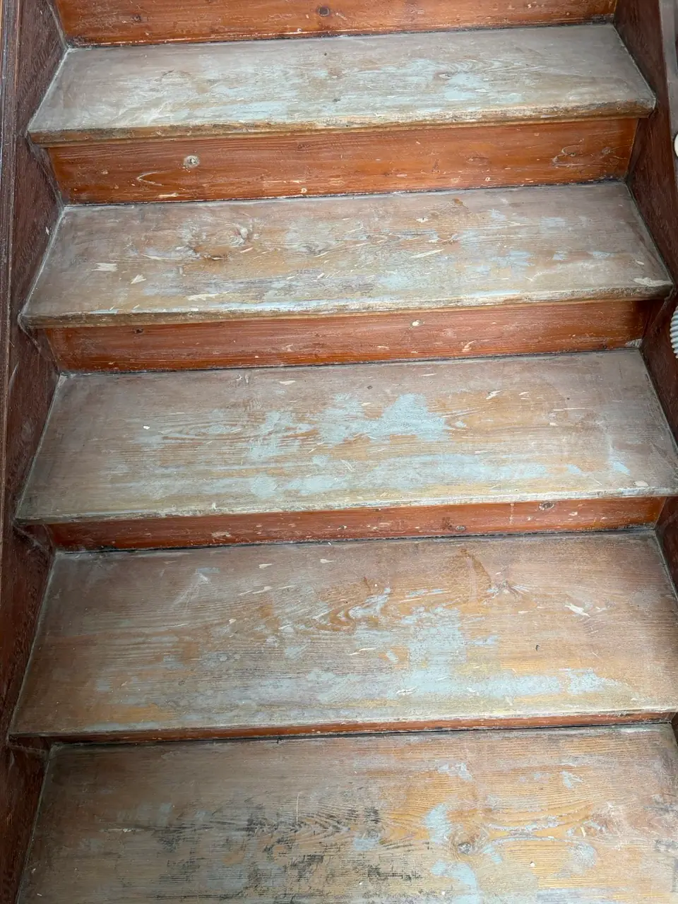 Nahaufnahme mehrerer abgenutzter Holzstufen mit hellen Abriebspuren auf den Trittflächen.