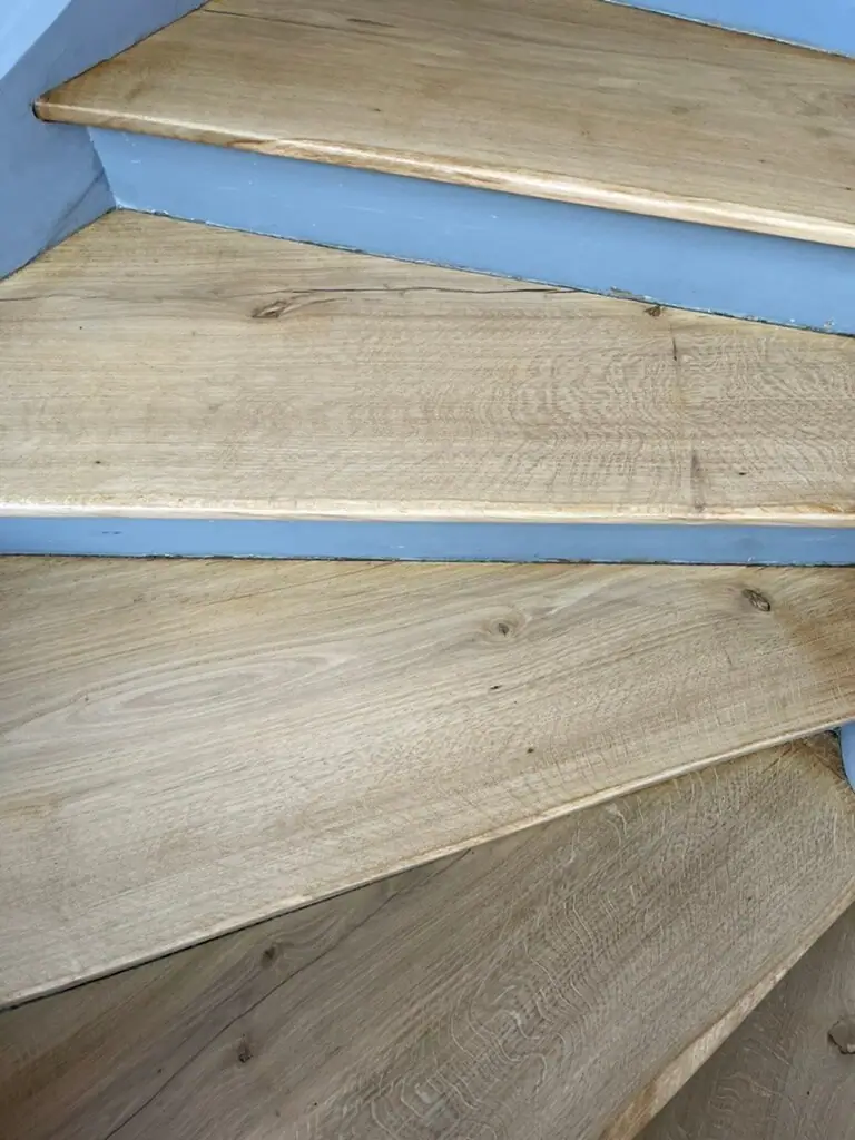 Detailansicht mehrerer heller Holzstufen mit sichtbarer Maserung und grauen Setzstufen.