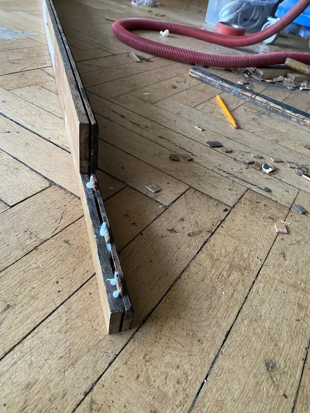 Nahaufnahme eines ausgebauten Parkettelements auf einem Holzfußboden.