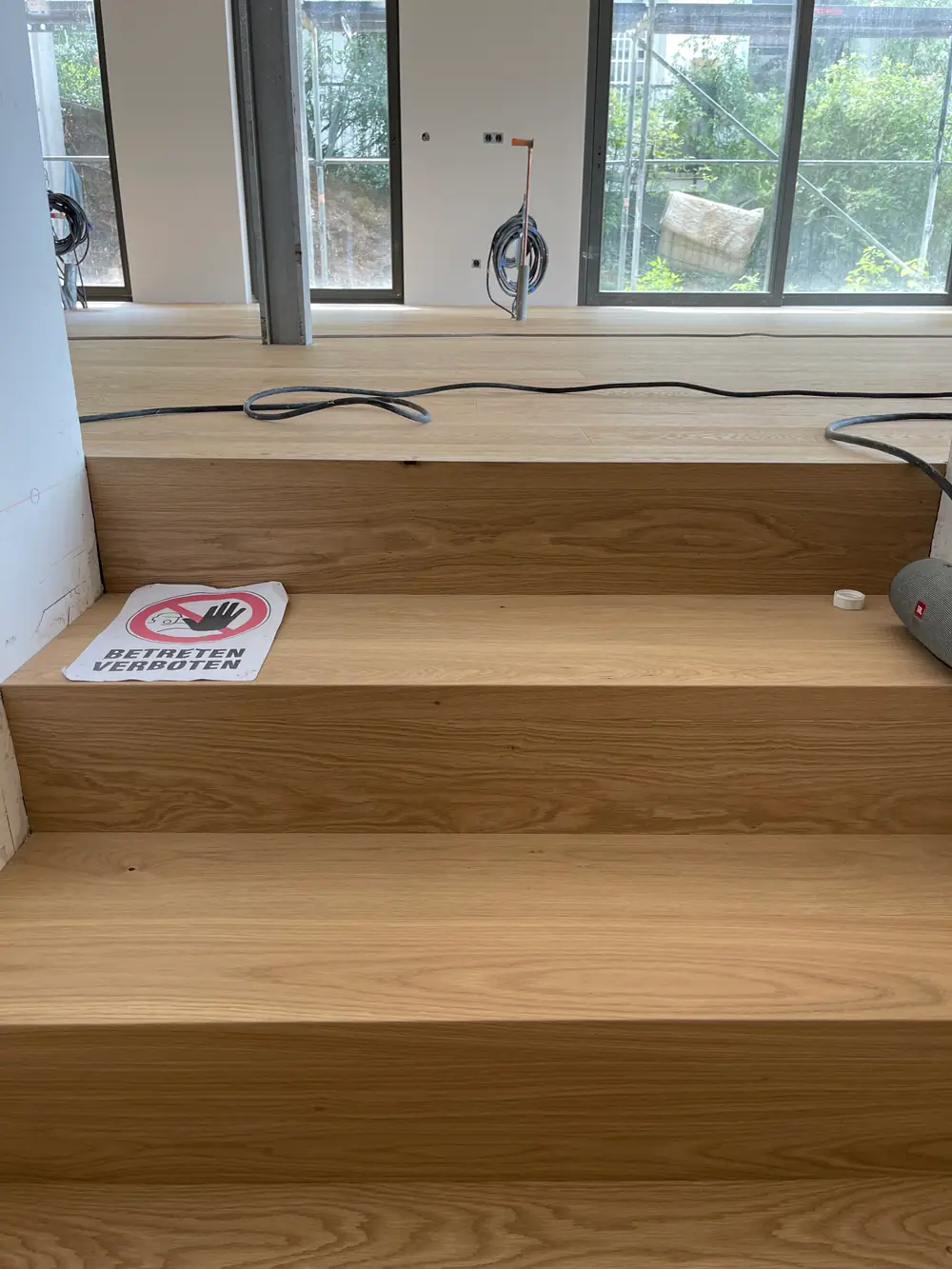 Breite Holzstufen mit sichtbarer Maserung und Kabeln auf den oberen Stufen.