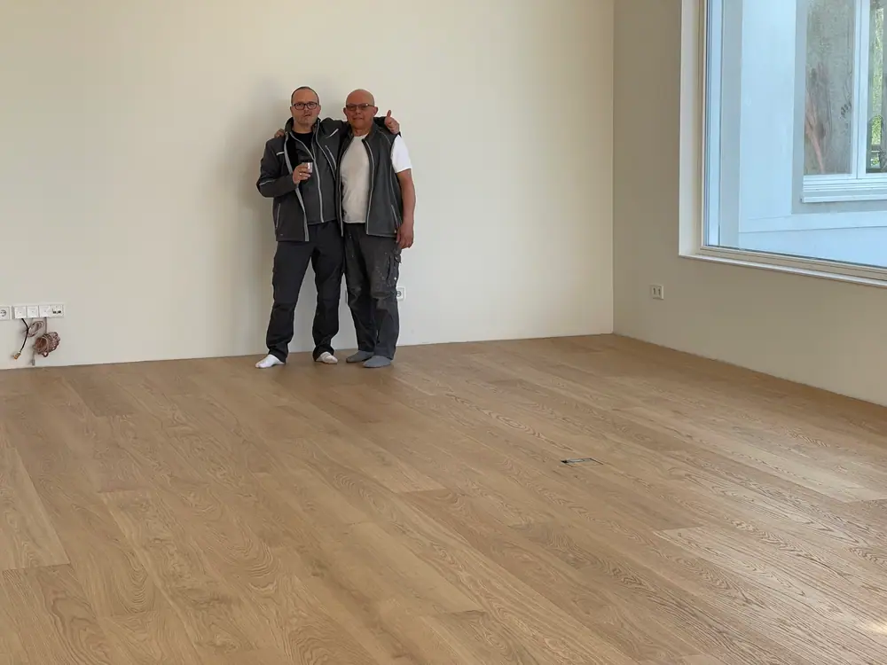 Heller Raum mit großflächig verlegten Eiche-Landhausdielen und zwei Personen.