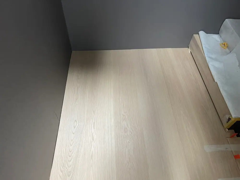 Helle Holzdielen in einem schmalen Bereich zwischen dunkelgrauen Wänden.