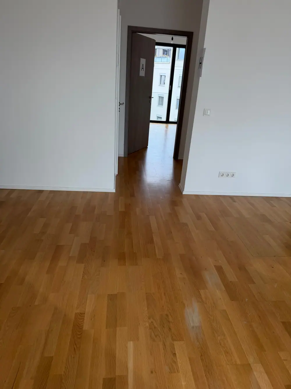 Blick über eine Parkettfläche durch einen Türdurchgang in einen weiteren Raum.