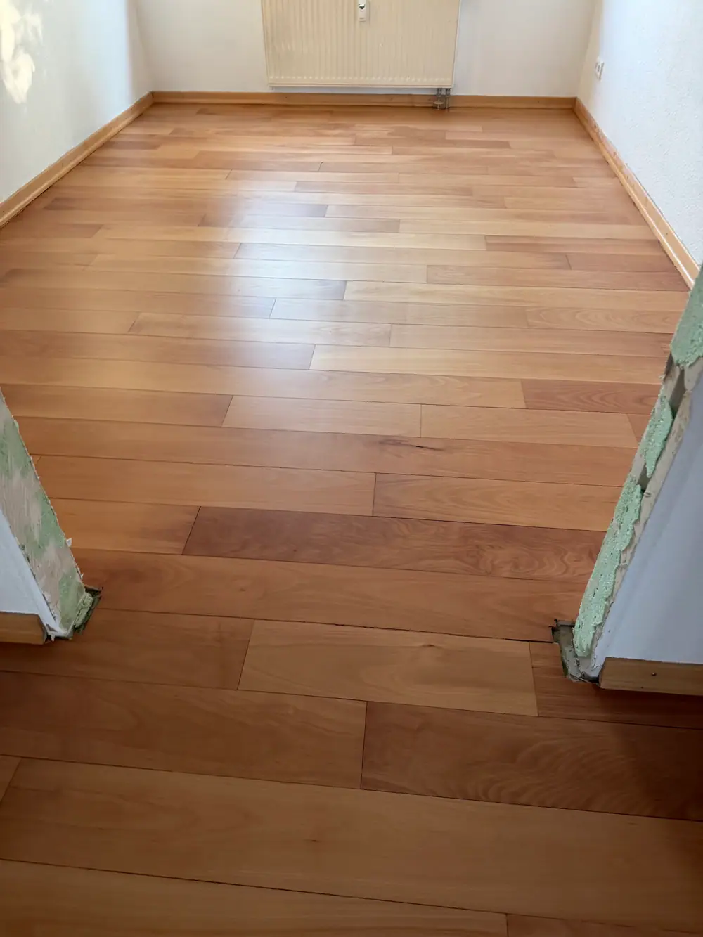 Ansicht einer Treppe mit Holzstufen, weißer Wand und Eichenparkett im Fischgrätmuster.
