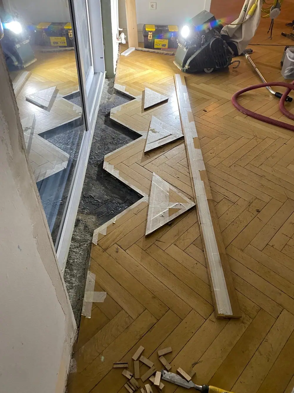 Geöffneter Bereich am Fensterelement mit herausgenommenen Parketteilen und Werkzeugen.
