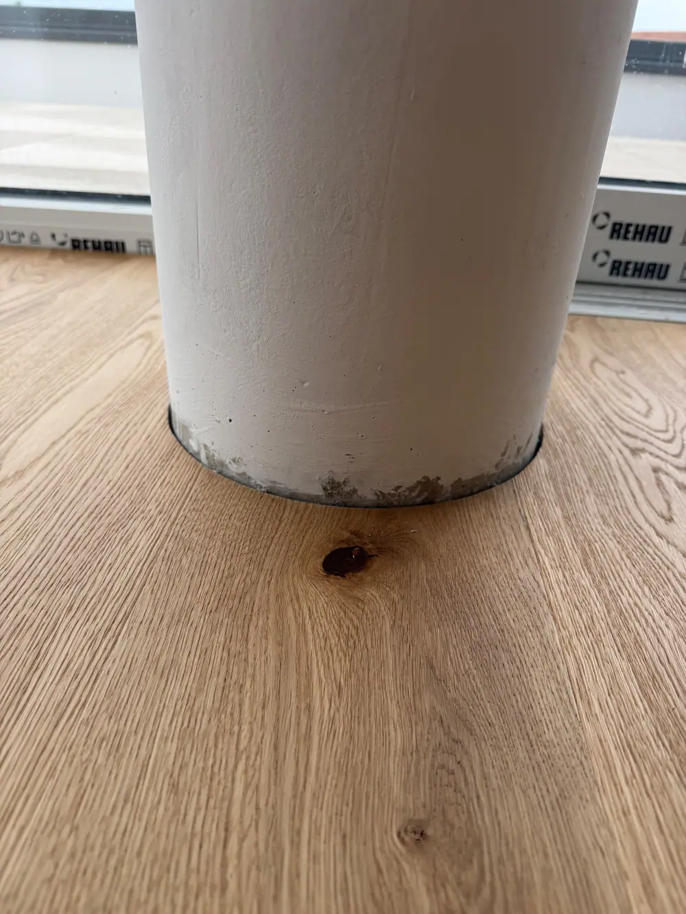 Nahaufnahme einer Eichen-Landhausdiele am Fuß einer runden Säule mit deutlich sichtbarer Maserung und Ast.