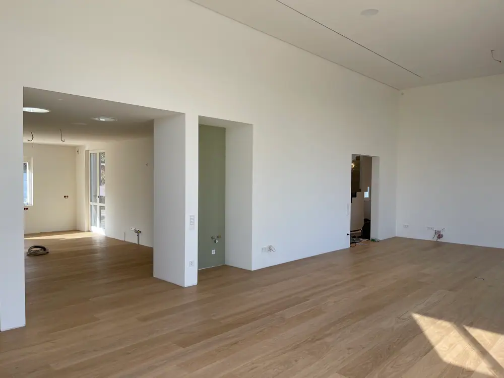 Großzügiger Innenraum mit Eiche-Landhausdielen, weißen Wänden und offenen Durchgängen.