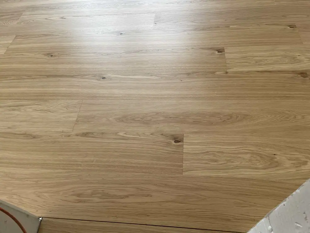 Draufsicht auf den hellen Holzboden mit breiten Dielen, sichtbarer Maserung und einzelnen Ästen.