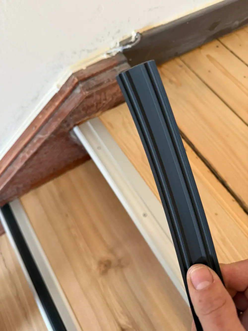 Unscharfe Nahaufnahme einer Holzstufe mit dunkler Gummieinlage und silberfarbenem Aluminiumprofil.