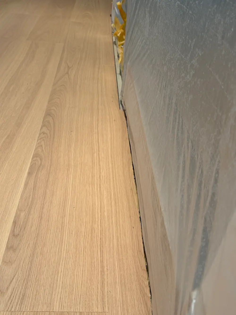 Nahaufnahme mehrerer heller Holzdielen mit sichtbarer Maserung und Wandanschluss.