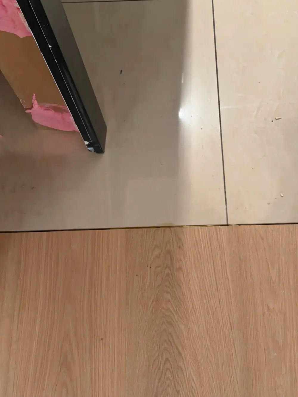 Helle Holzdielen treffen an einer schmalen Fuge auf großformatige helle Bodenfliesen.