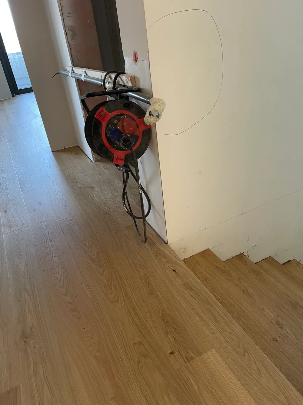 Dielenboden am Treppenabgang mit Kabeltrommel, Kabeln und unfertigen Wandanschlüssen.