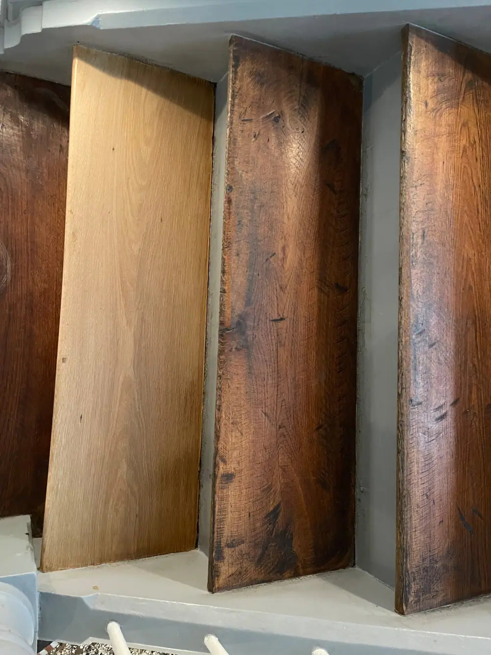 Mehrere hochkant stehende Holzstufen zeigen unterschiedliche helle und dunkle Oberflächen sowie sichtbare Gebrauchsspuren.